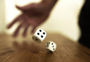 A man rolling dice on a table, signifying odds of winning a workers' comp case.