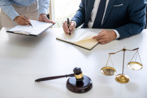 Fiscal trabajando en su escritorio con un martillo y una balanza de la justicia en primer plano