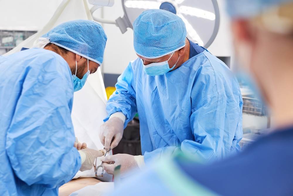 Surgeons and nurses working in an operating room, perhaps on a workers' comp patient.