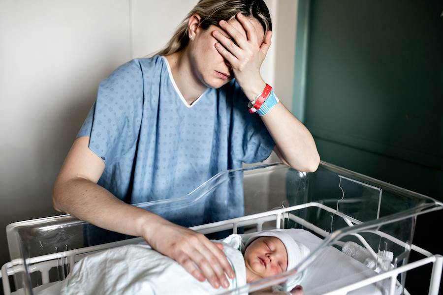 Sad mother near her newborn in hospital