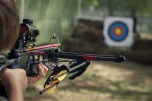 A man shooting his crossbow, legally, at a target practice facility.