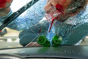 Peatón herido con la cabeza en el parabrisas destrozado de un coche, con dos botellas de cerveza vacías en el tablero - los efectos de conducir bajo los efectos del alcohol