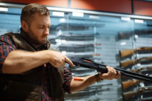 Hombre carga nuevo rifle en mostrador de tienda de armas