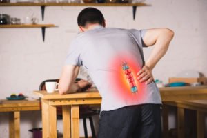 A man reaching for his back in pain due to a herniated disc.