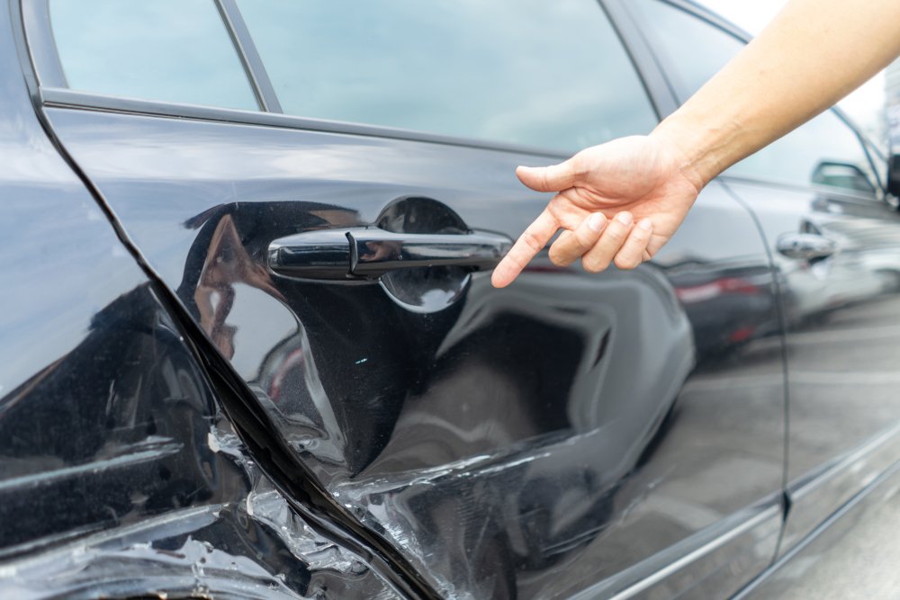 A parked car showing body damage due to a hit and run.