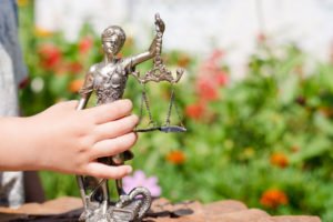 Kid's hand holding small statue of Lady Justice