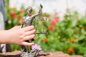 Mano de niño sosteniendo una pequeña estatua de Lady Justice