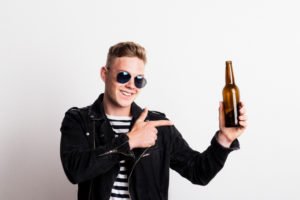 A young man holding a bottle of beer.