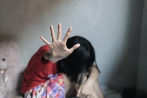 Una niña asustada en la cama con la mano extendida