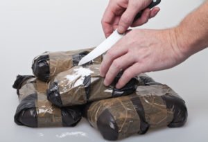 Police cutting cocaine packets with a knife