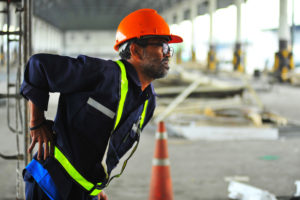 A construction worker holding his lower back in pain.