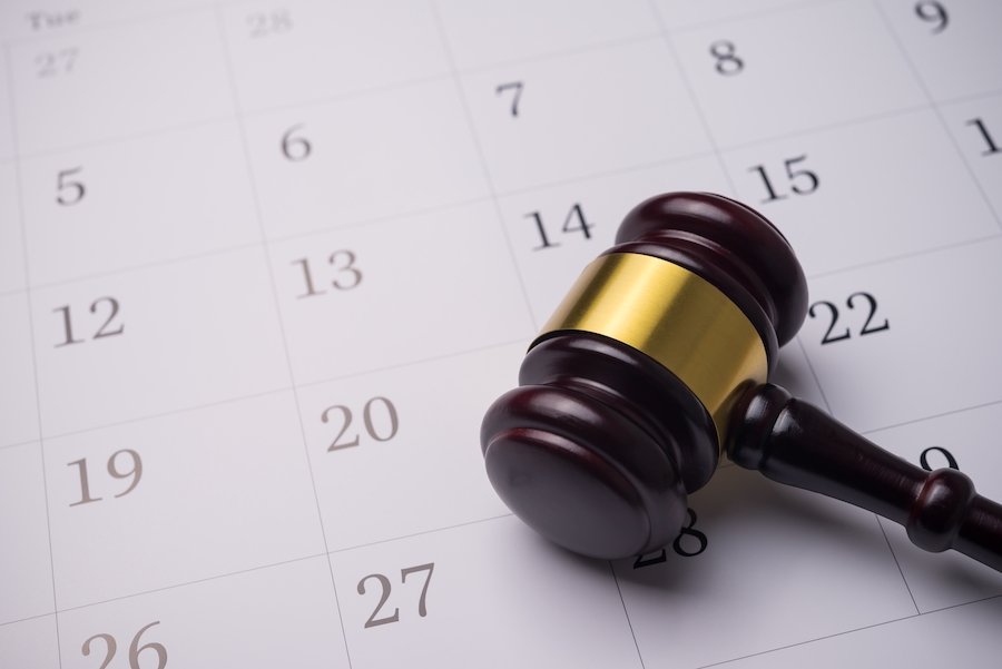 judge's wooden and gold gavel resting on a desk calendar