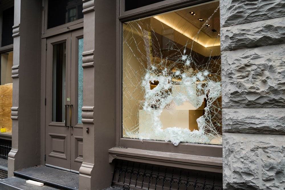 Broken windows in a city center caused by vandals, an example of criminal mischief.