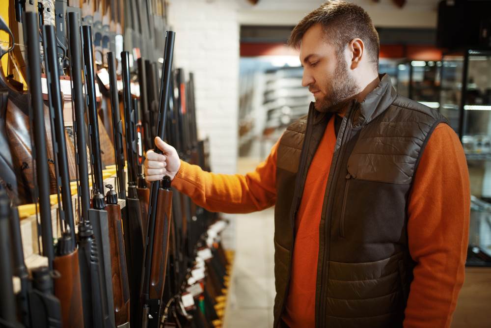 A man, possibly a felon, browsing through a gun store.
