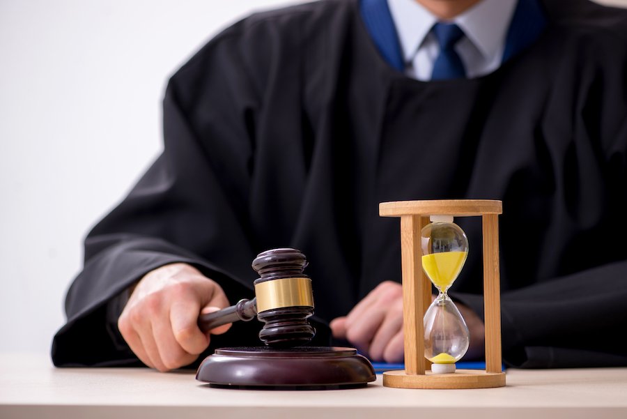 Judge in a robe hammering down his gavel next to an hourglass with time running out