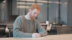 A man writing a sentence modification letter to give to the judge.