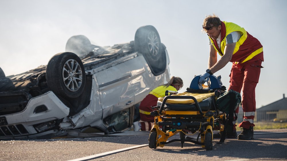 Paramedics pulling out a stretcher alongside a major car accident scene.