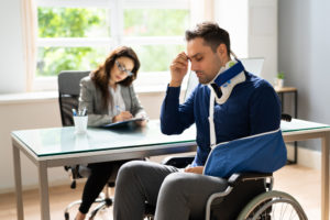 A man sitting in a wheelchair at his attorney's office after a slip-and-fall injury.