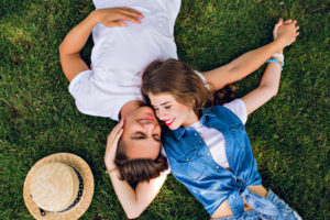 Overhead view of two happy teenagers romancing each other on the grass.