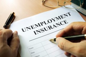Man's hand filling out form that says "unemployment insurance"