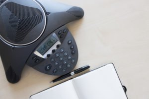 Teléfono que dice "llamada en conferencia" en el escritorio