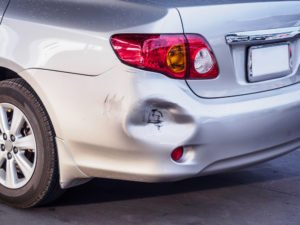 A car with a dented rear bumper, possibly due to a hit and run.