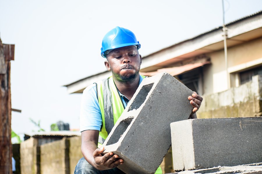 Man with hard hat holding a cinderblock