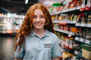 A young part time employee working at a retail store.