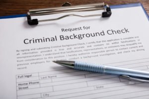 A criminal background check application on a clipboard with a pen resting on it