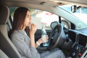 A young woman taking an Adderall pill while she is in her car, possibly leading to an Adderall DUI.