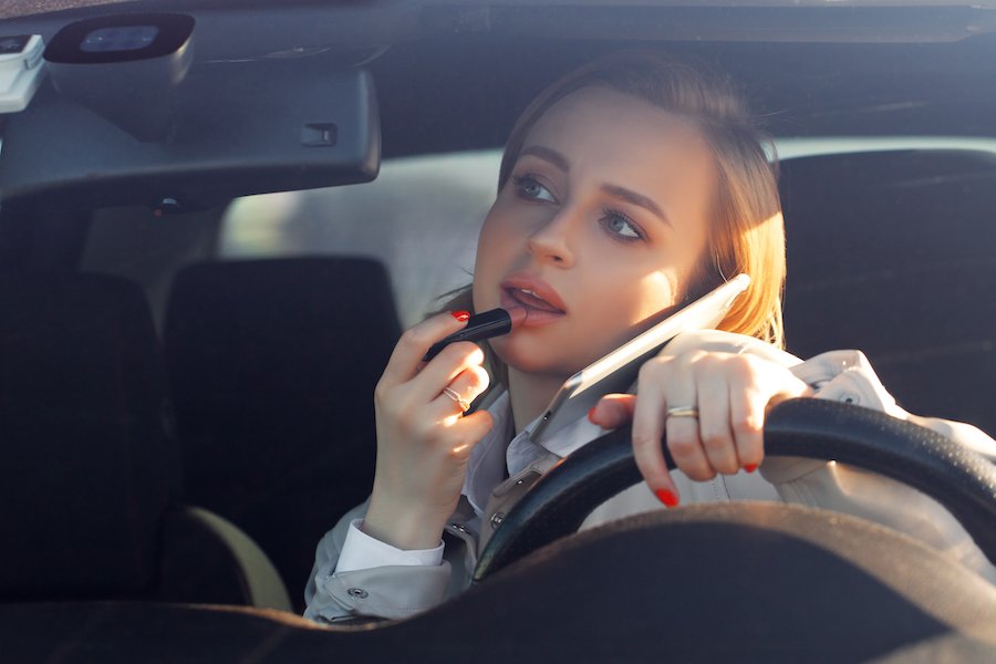Woman applying lipstick while driving