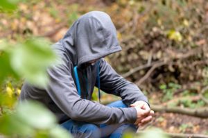 Fugitivo con capucha escondido en el bosque