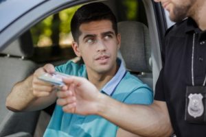 Driver handing driver's licenes to police during traffic stop