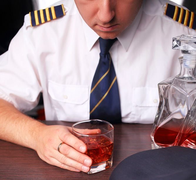 Un piloto tomando un vaso de whisky antes de un vuelo, posiblemente llevando a un FUI si es atrapado.