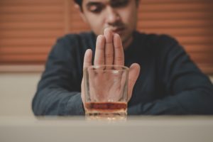 Hombre empujando un vaso de alcohol
