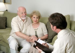 A senior couple talking with a salesperson in their home.