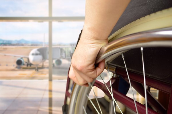 Injured worker in wheelchair at airport waiting to travel out-of-state for medical care