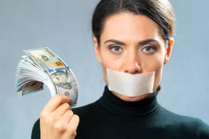 Woman holding with tape over her mouth, signifying she will not testify in exchange for money