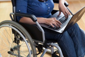 An injured worker working on her laptop while sitting in a wheelchair.