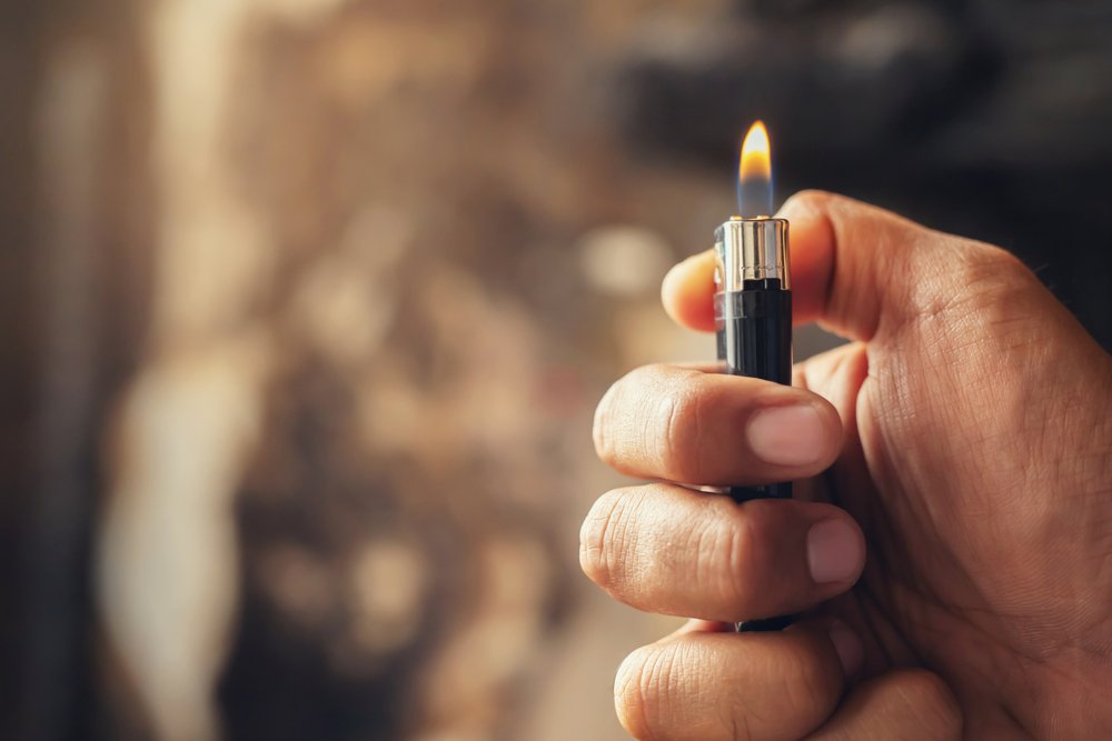 A person holding up a lighter to potentially start a fire.
