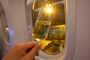 Hand holding glass of champagne on airplane