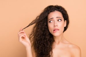 Unhappy woman holding her frizzy hair