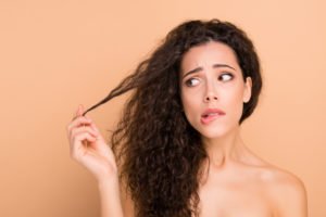 Unhappy woman holding her frizzy hair