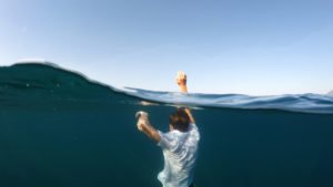 A boy drowning in a lake or sea.