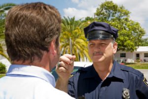 Oficial de policía sosteniendo una pluma y realizando una prueba de sobriedad en el campo a un automovilista.