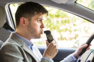 Man blowing into an ignition interlocking device prior to starting his car.