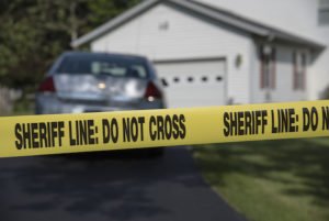 House with yellow tape that says "sheriff line: do not cross"