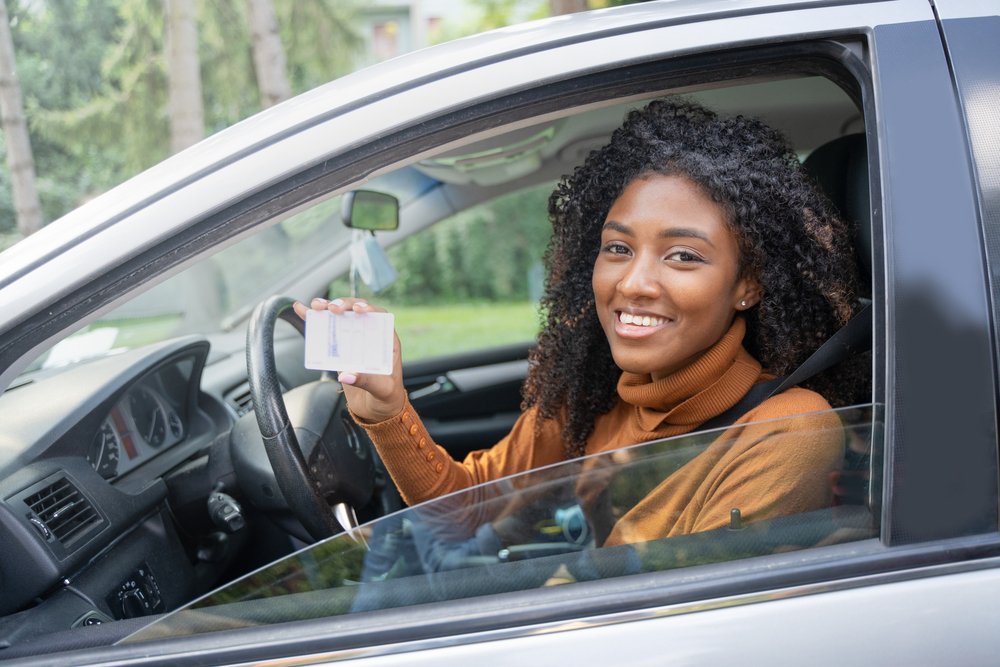 A happy driver holding up her recently reinstated driver's license.