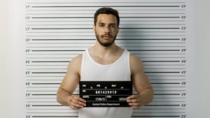 A bruised man holding up a placard while his mugshot is being taken at the police station during his booking.