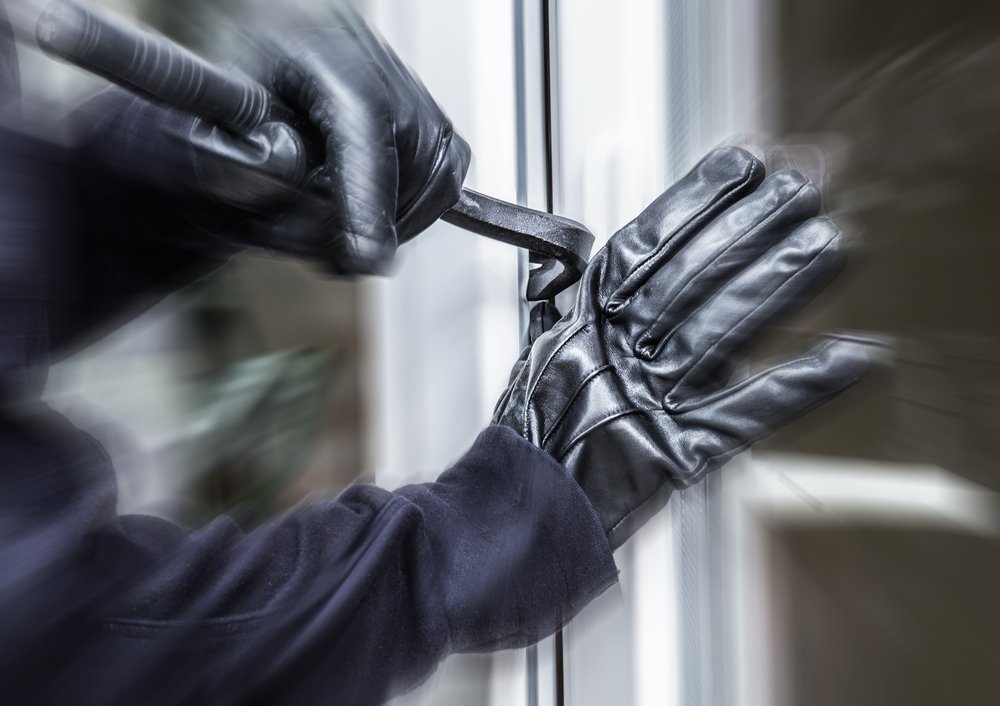 A burglar breaking through a door with a pry bar.